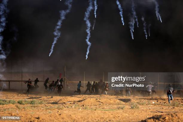 Picture taken on July 13, 2018 shows tear gas canisters fired by Israeli forces landing amidst protesters during a demonstration along the border...