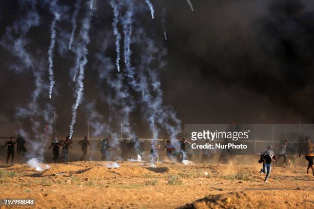 Picture taken on July 13, 2018 shows tear gas canisters fired by Israeli forces landing amidst protesters during a demonstration along the border...
