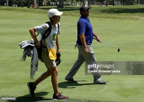 Elias Francque, a 17-year-old high school student caddies for Steven Bowditch of Australia on the 18th hole during the second round of the John Deere...