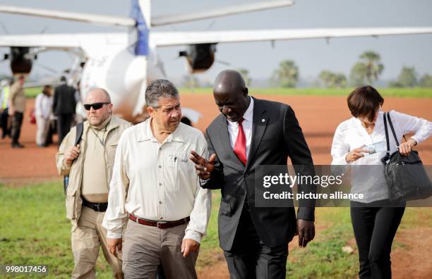 German foreign minister Sigmar Gabriel and the Ugandan minister responsible for refugee matters Ecweru Musa Francis chat as they walk at the airport...