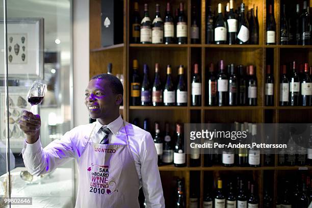 Luvo Ntezo, a wine sommelier at the Twelve Apostles Hotel, stands with a glass of red wine in a wine cellar on March 23, 2010 in Cape Town, South...