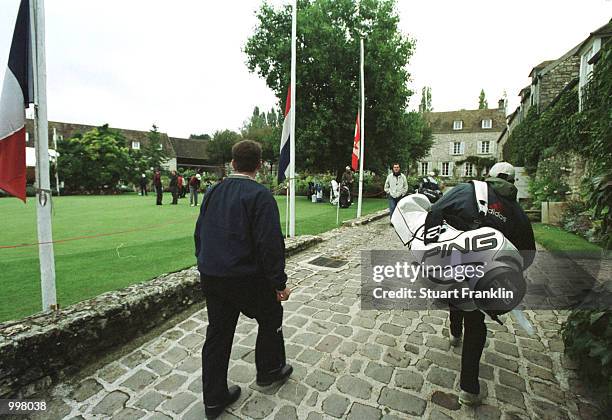 Player and caddie walk to the practice putting green in front of the flags raised to half mast at the Saint-nom-la-breteche Golf Club in Paris,...