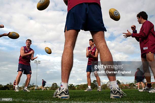 Mick Martin, Clint Alleway and Shannon Rusca of the Brisbane Lions take part in a passing drill during the Brisbane Lions training session at Giffin...