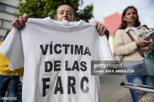 Woman holds a T-shirt reading "Victim of the FARC" during a protest outside at the Special Jurisdiction for Peace headquarters in Bogota on July 13,...