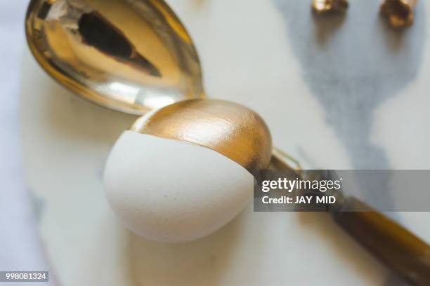 easter: place setting, elegant gold and white egg, on marble pla - white gold stock pictures, royalty-free photos & images