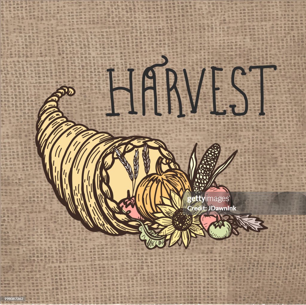 Autumn harvest cornucopia with hand lettered greeting burlap background