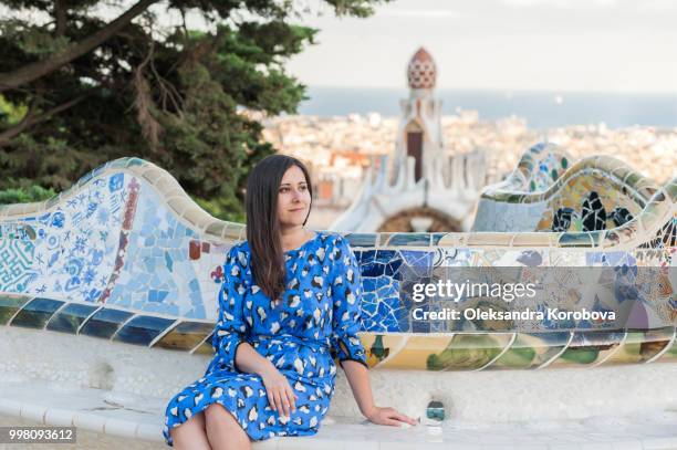 fashionable young woman relaxing on the mosaic wave bench in park gruell in barcelona, spain. - park guell stock pictures, royalty-free photos & images