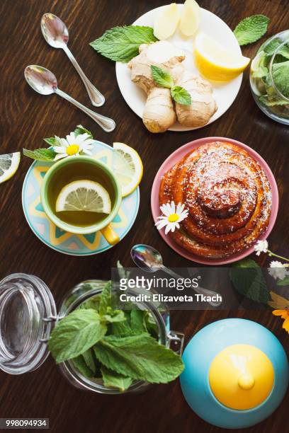 cup of herbal tea with lemon and mint leaves, ginger root and baked good - lemon mint stock pictures, royalty-free photos & images