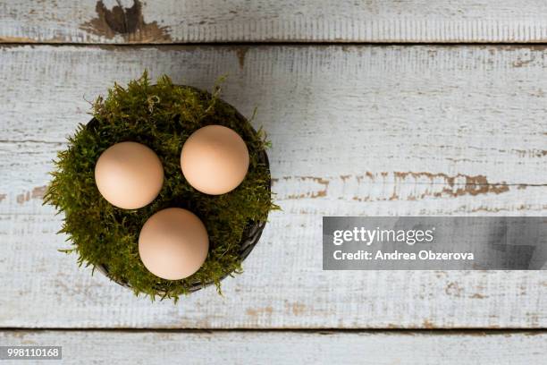 three easter eggs in a moss basket, happy easter concept, retro easter background - empty easter basket stock pictures, royalty-free photos & images