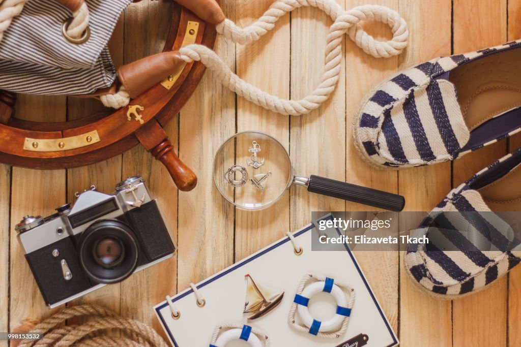 Striped slippers, camera, bag and maritime decorations on the wooden background