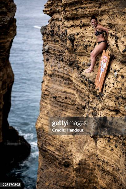 In this handout image provided by Red Bull, Jacqueline Valente of Brazil reacts while preparing to dive from a 21 metre cliff on Islet Vila Franca do...