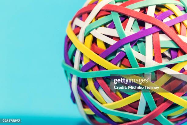 rubber band ball on blue background - rubber band stockfoto's en -beelden