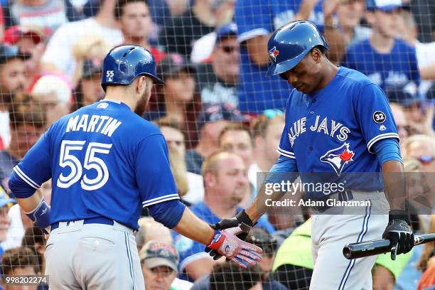 Russell Martin high fives Curtis Granderson of the Toronto Blue Jays after scoring in the second inning of a game against the Boston Red Sox at...