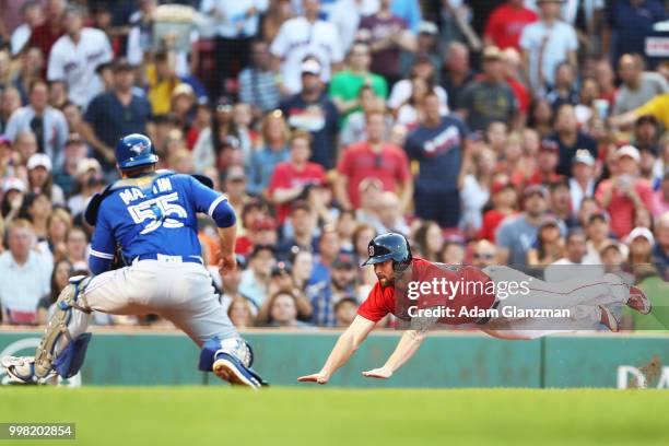 Sam Travis of the Boston Red Sox slides safely past the tag of Russell Martin of the Toronto Blue Jays in the second inning of a game at Fenway Park...