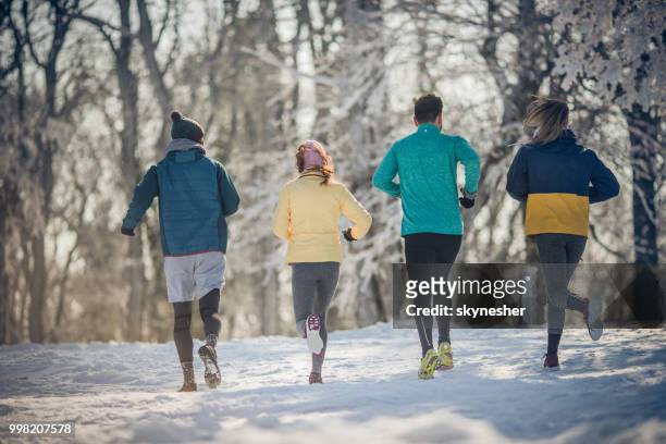 rückansicht des athletischen freunde im winter tag im freien laufen. - skynesher stock-fotos und bilder