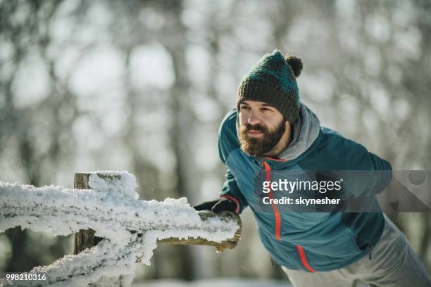 junger sportlicher mann aufwärmen vor sport-training im winter. - skynesher stock-fotos und bilder