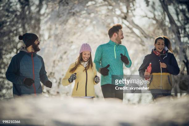 gruppe von glücklichen athleten sprechen beim joggen im wintertag im park. - skynesher stock-fotos und bilder