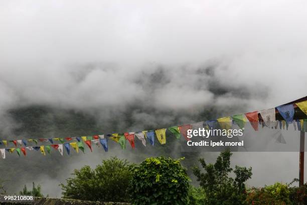 view of prayer flags at trongsa dzong with foggy hills, bumthang - ipek morel stock pictures, royalty-free photos & images