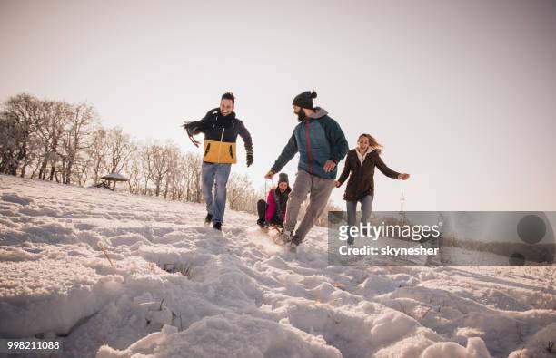 junge fröhliche freunde, die spaß beim laufen auf dem schnee. - skynesher stock-fotos und bilder