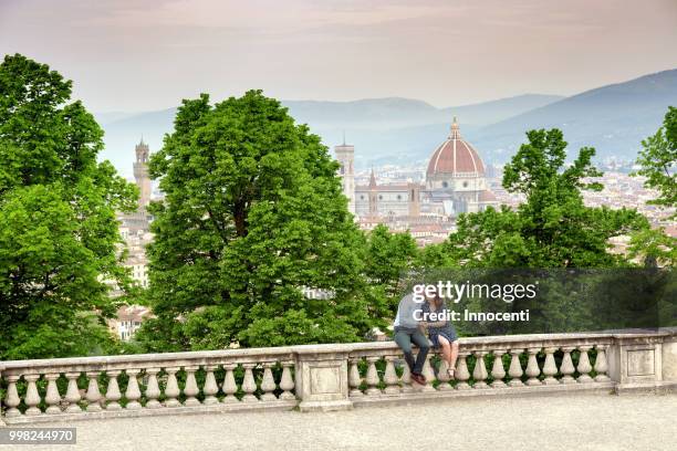 young man kissing woman, santa maria del fiore in background, florence, toscana, italy - fiore stock-fotos und bilder