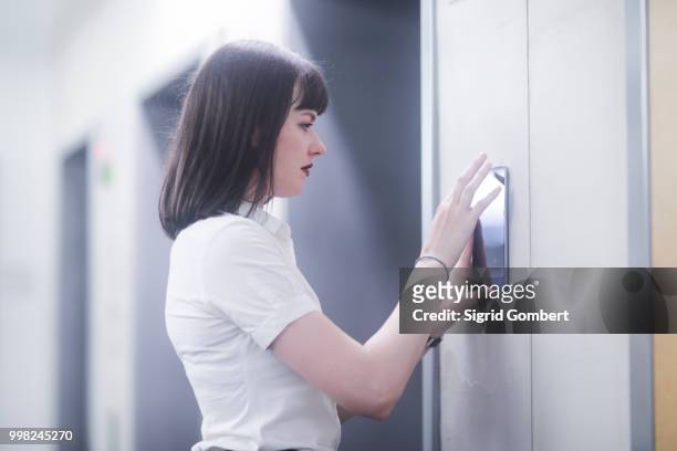 woman using wall mounted touch screen control panel - sigrid gombert fotografías e imágenes de stock