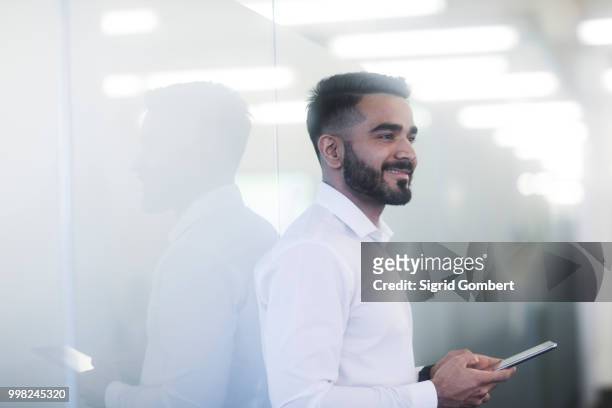 young man using mobile phone in office - sigrid gombert stock-fotos und bilder