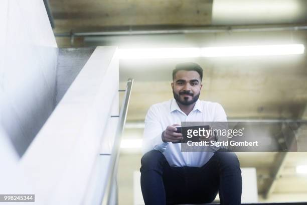young man using digital tablet in office - sigrid gombert photos et images de collection