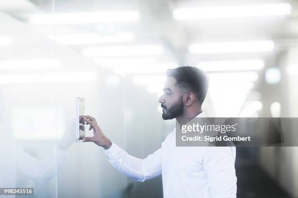 young man using digital tablet in office - sigrid gombert stock-fotos und bilder