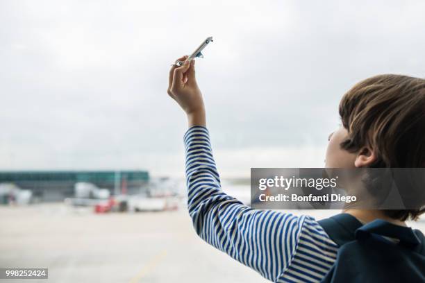 boy playing with toy airplane in airport departure lounge - model airplane stock pictures, royalty-free photos & images