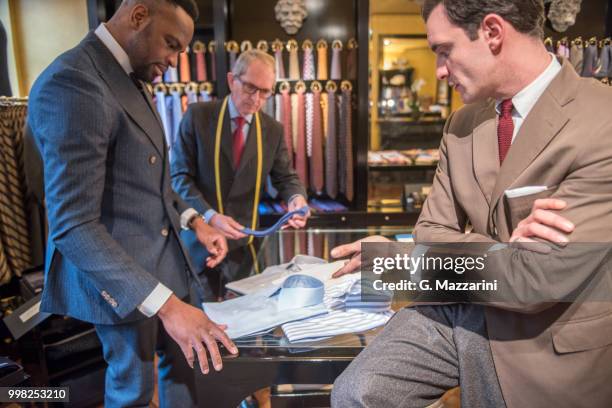 tailor and customer looking at shirts in tailors shop - g man foto e immagini stock