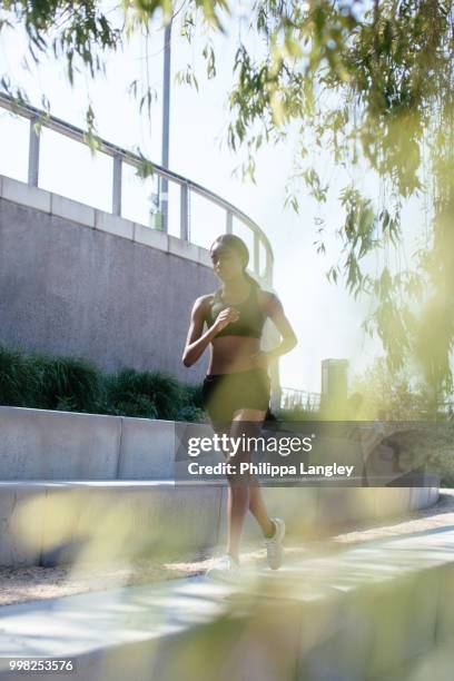 young woman running in park - differential focus stock pictures, royalty-free photos & images