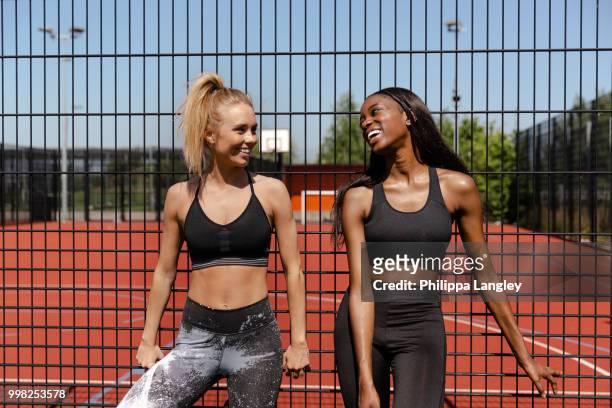young women chatting by basketball court - sportbeha stockfoto's en -beelden