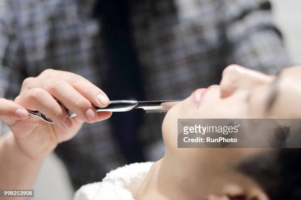 barber shaving clients face with straight razor in barber shop - straight razor stock pictures, royalty-free photos & images