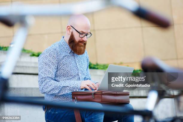 bearded man using laptop outdoors - gpointstudio imagens e fotografias de stock