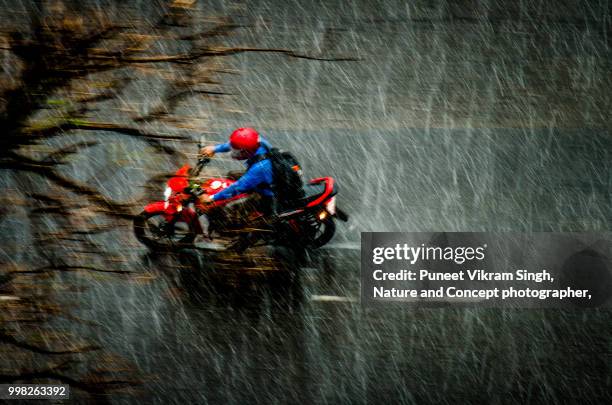 a biker riding a bike on a slippery road during heavy rainfall in mumbai - india rain stock pictures, royalty-free photos & images