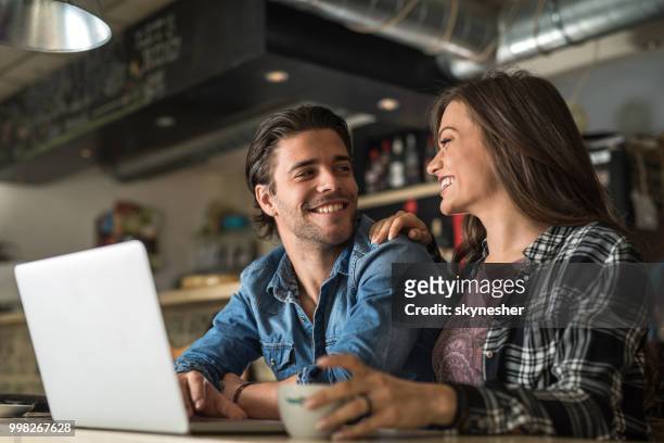 glückliches paar in liebe kommunikation während der benutzung des computers in einem café. - skynesher stock-fotos und bilder