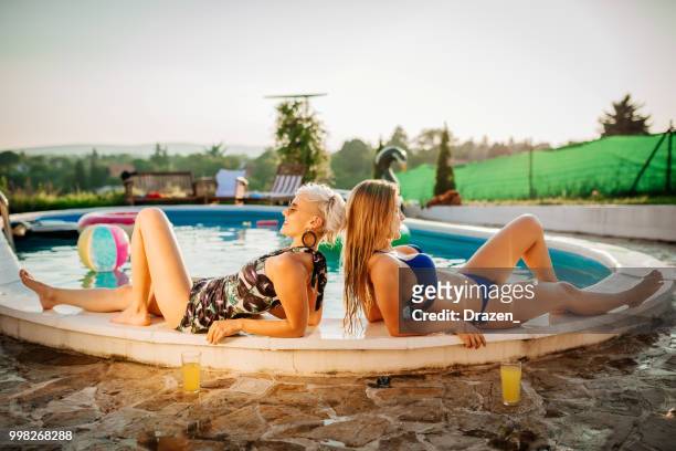 zwei girlfirends in badeanzügen pool sonnenbaden - drazen stock-fotos und bilder