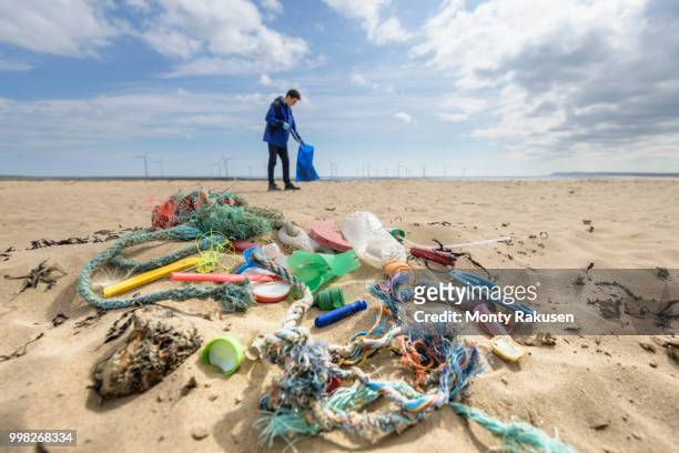 man picking up plastic pollution collected on beach, north east england, uk - plastic pollution beach stock pictures, royalty-free photos & images