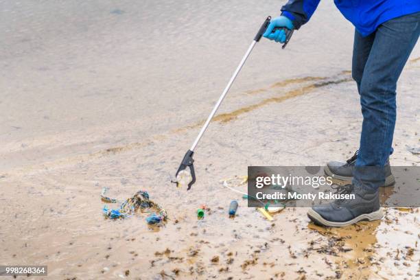 man using litter picker to remove plastic pollution collected on beach, north east england, uk - east beach stock pictures, royalty-free photos & images