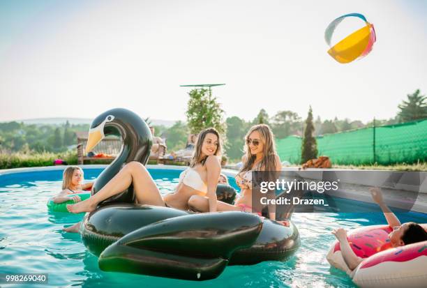 two friends enjoy the pool party on pool float - drazen stock pictures, royalty-free photos & images