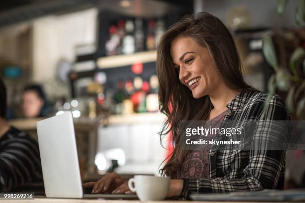 glückliche mädchen lesen einer e-mail auf laptop in einem café. - skynesher stock-fotos und bilder