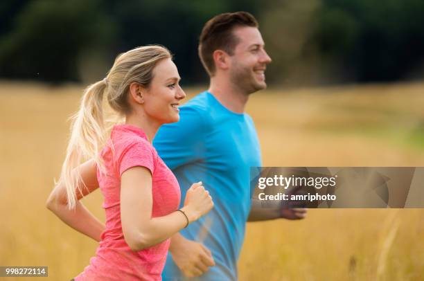 side view upper body jogging couple in high dry grass - couple exercising 30s stock pictures, royalty-free photos & images