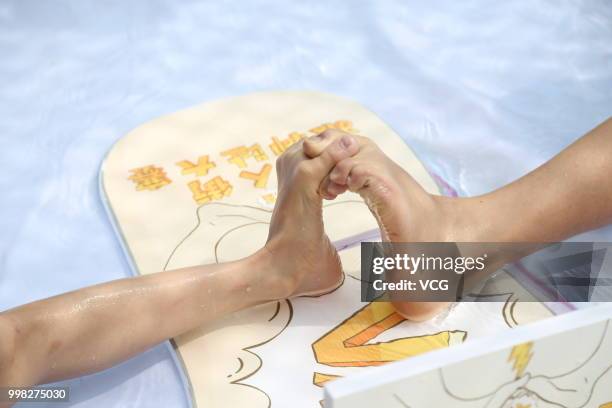 People compete in a toe wrestling competition at a water park on July 11, 2018 in Chongqing, China.