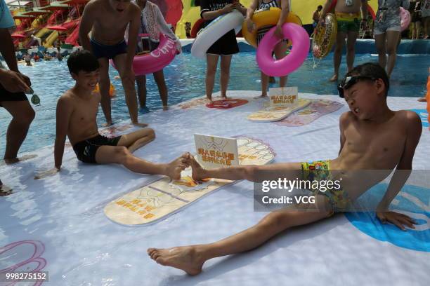 People compete in a toe wrestling competition at a water park on July 11, 2018 in Chongqing, China.