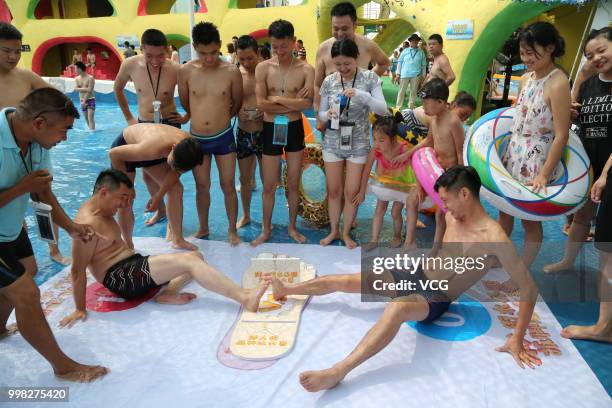 People compete in a toe wrestling competition at a water park on July 11, 2018 in Chongqing, China.