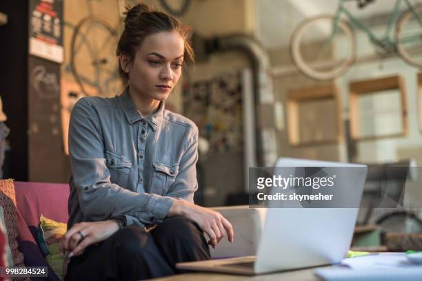 ernsthafte geschäftsfrau surfen im internet mit laptop im casual büro. - skynesher stock-fotos und bilder