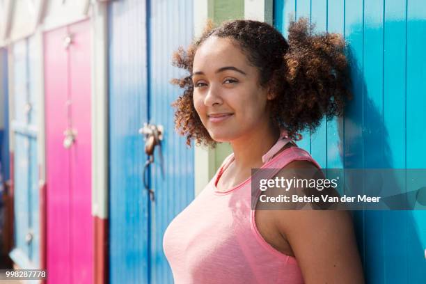 portrait of smiling mixed race woman leans against beach hut. - meer photos et images de collection