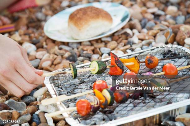 close up of hand turning skewers on barbecue grill on beach. - meer photos et images de collection