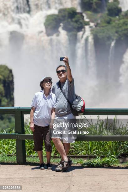 brasilien paar touristen stehen vor wasserfälle von iguacu in den ferien nehmen selfie - grafissimo stock-fotos und bilder