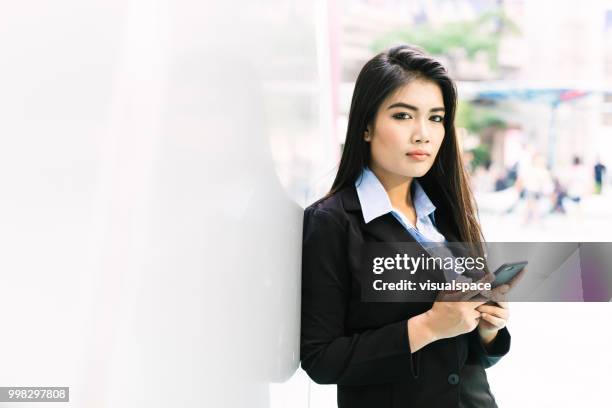 jovem mulher asiática, inclinando-se contra uma parede, ao verificar o telefone dela. - vanguardians - fotografias e filmes do acervo